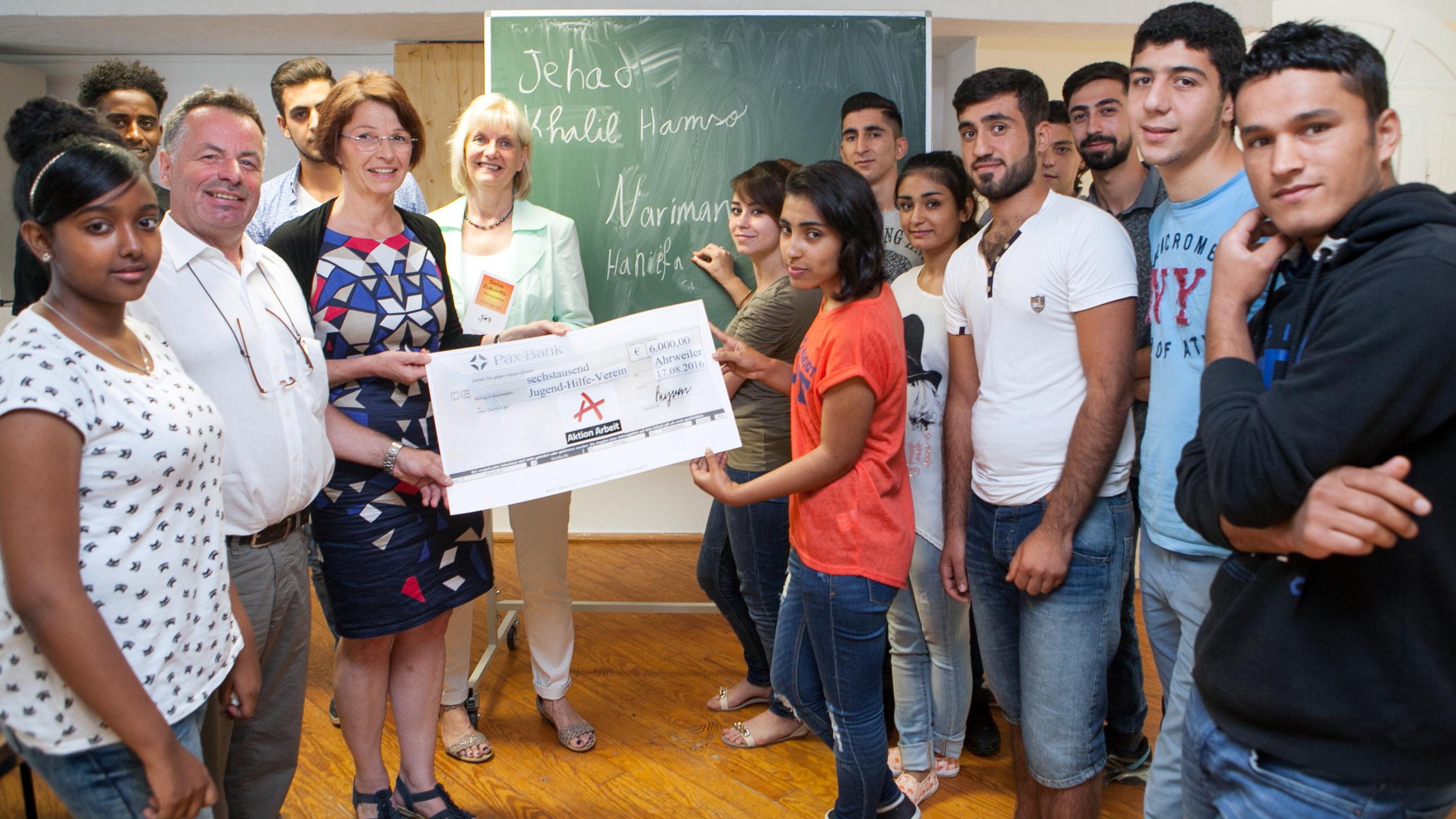 Friedhelm Münch, Andrea Steyven und Petra Rademacher mit den Jugendlichen aus Syrien, Eritrea und Afghanistan bei der Scheckübergabe